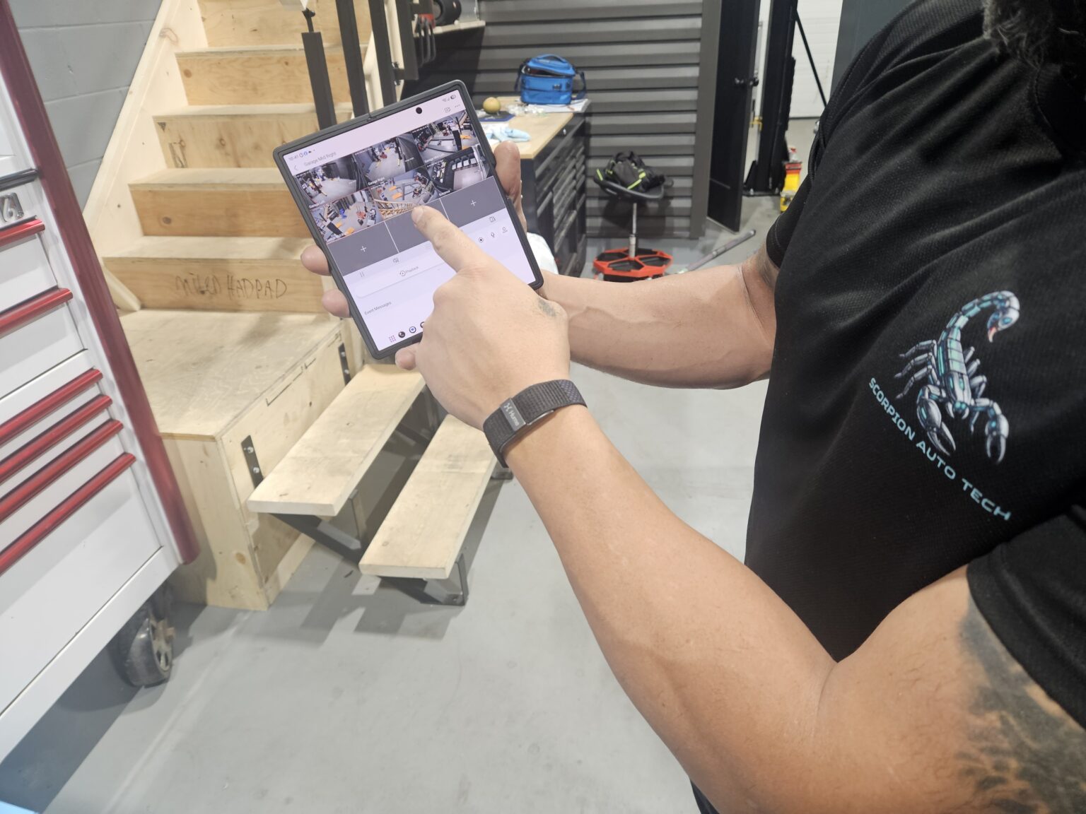 Ottawa auto shop owner checking his security cameras live on a tablet after installation by AV Geeks